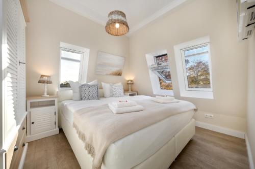 青斯特Villa Strandblick 12的白色卧室设有一张白色大床和两个窗户