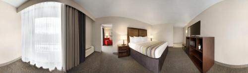 厄兰格Country Inn & Suites by Radisson, Erlanger, KY的酒店客房设有床和窗户。