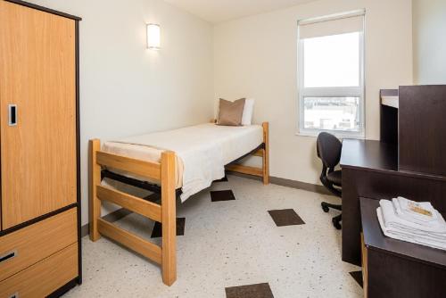 温尼伯UWinnipeg Downtown Hostel的一间小卧室,配有床和窗户