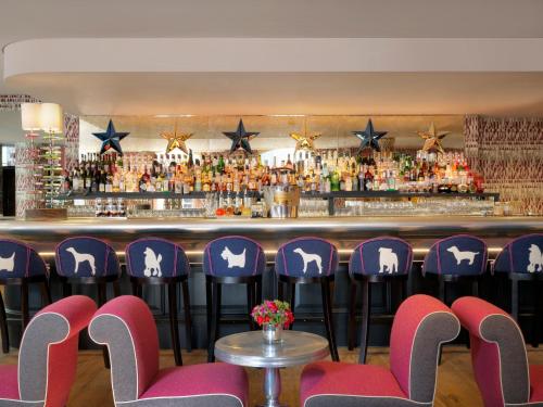 伦敦菲尔姆戴尔酒店集团禧市酒店的酒吧前的酒吧配有紫色椅子