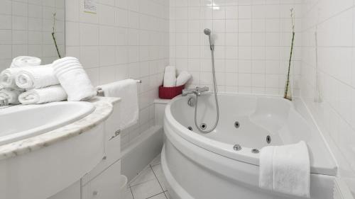 讷沙托Hôtel Restaurant L'Evidence的白色的浴室设有浴缸和水槽。