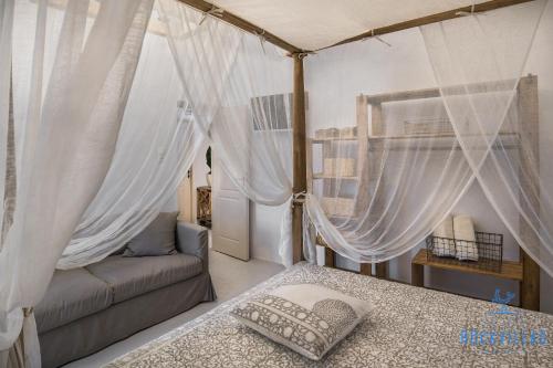 安坡里奥圣托里尼Rock Villas - Complex的一间卧室配有天蓬床和沙发