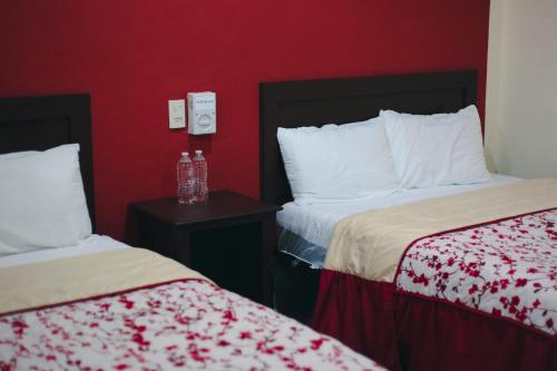 坎佩切Hotel Maya Becan的酒店客房设有两张床和红色的墙壁。