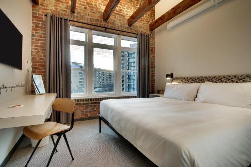 华盛顿凤巢酒店的一间卧室配有一张床、一张书桌和一个窗户。