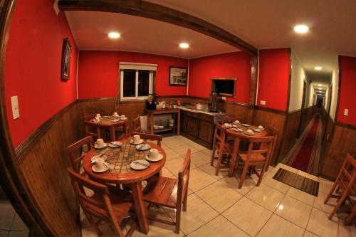 纳塔列斯港Hostal America en Puerto Natales的一间拥有红色墙壁和木桌及椅子的用餐室