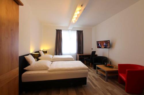 格拉德贝克Hotel Jammerkrug的酒店客房,设有两张床和一张红色椅子