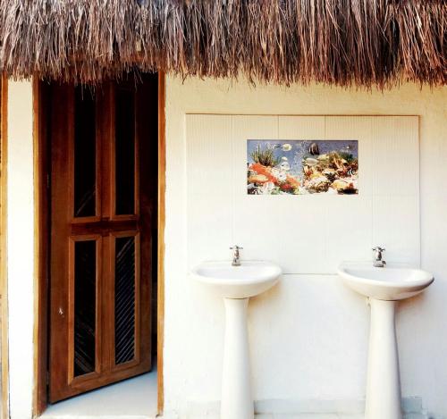 帕洛米诺Hostal Nibuni Palomino的浴室设有两个水槽和茅草屋顶。