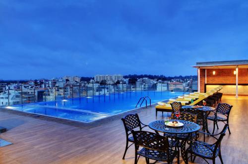 班加罗尔Hotel Royal Orchid Bangalore的一个带桌椅的阳台和一个游泳池