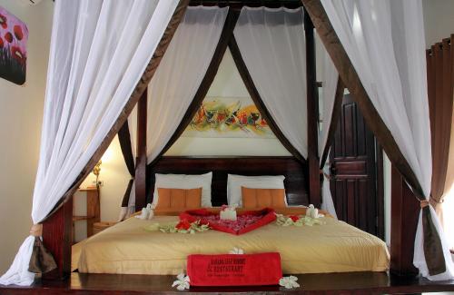 吉利特拉旺安蕉叶度假村的一间卧室配有带鲜花的天蓬床