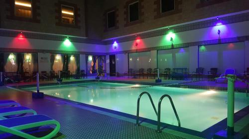 马斯喀特苎麻集团盖斯特林酒店的大楼内一个带椅子和灯的游泳池