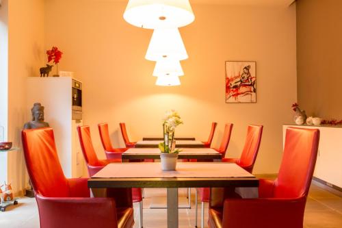 布鲁日阿斯内洛床和早餐的一间带桌子和红色椅子的用餐室