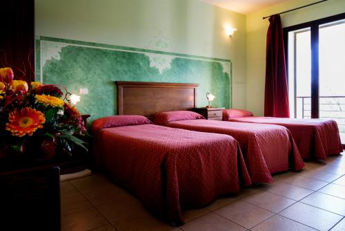 斯佩基亚萨兰托酒店的一间设有三张床的客房,配有红色床单和鲜花