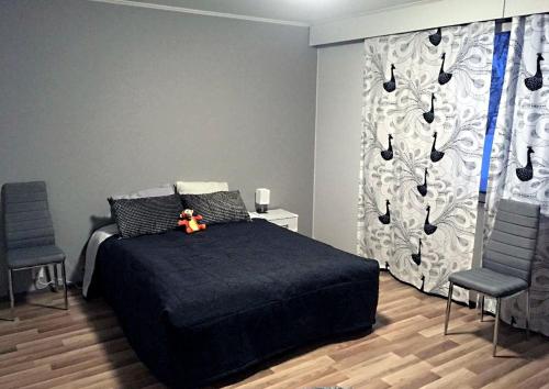 库萨莫Villa Porkka的一间卧室配有一张黑色的床和两把椅子