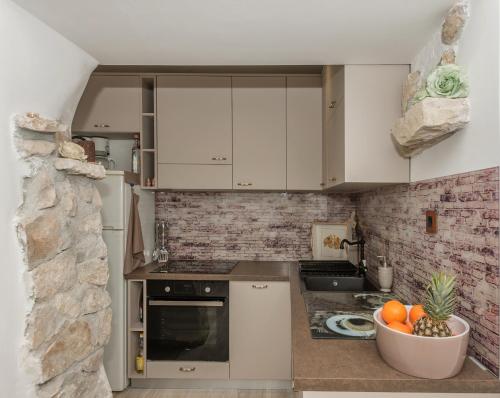马卡尔斯卡Apartman Teta Jadre的厨房配有白色橱柜和一碗水果