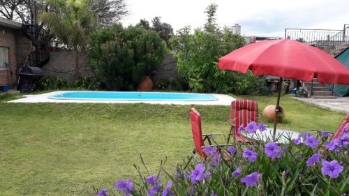 卡塔马卡La Chacarita apart的一个带红色遮阳伞和椅子的庭院和一个游泳池