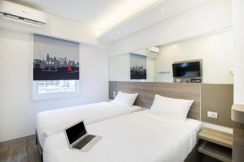 马尼拉Red Planet Manila Bay的一张位于酒店客房内的两张床,床上配有一台笔记本电脑