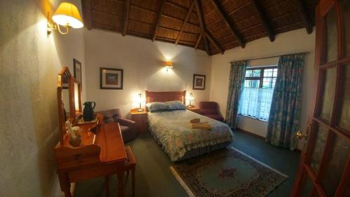 Kyalami橡树宾馆的一间卧室配有一张床、一张桌子、一张床和一个窗户。
