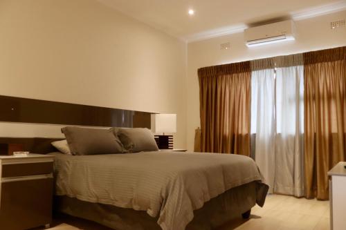 卢萨卡AMB Apartments的一间卧室设有一张大床和一个窗户。