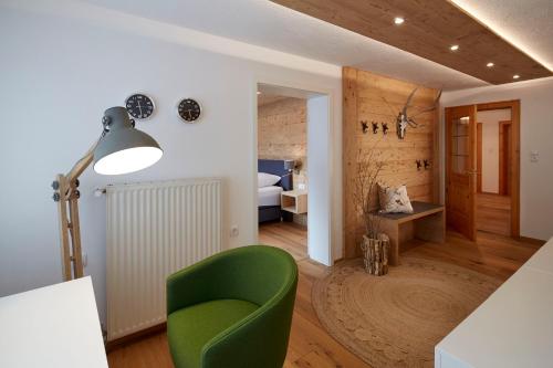 菲尔斯Alpenchalet Vils Tirol的一间带绿色椅子的客厅和一间卧室