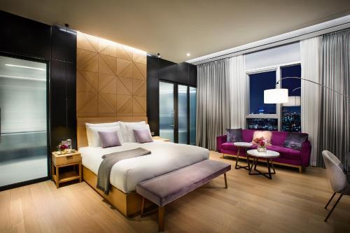 首尔L7 Gangnam的一间卧室配有一张大床和一张紫色沙发