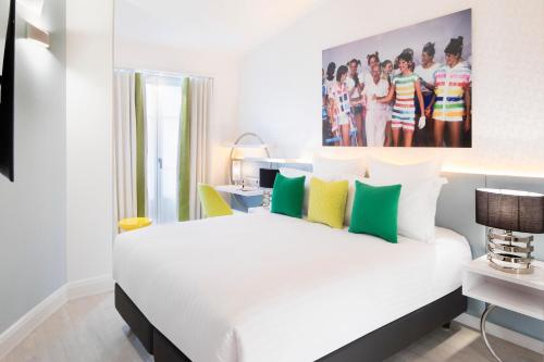 巴黎Hôtel Dress Code的一间卧室配有白色的床和绿色和黄色枕头
