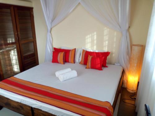 迪亚尼海滩Sea Breeze Villas Kenya的一间卧室配有红色和橙色枕头的床