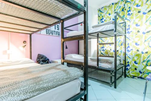 那不勒斯太阳旅馆的一间卧室设有双层床和色彩缤纷的墙壁。