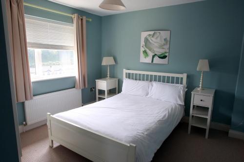 邓莫尔东Glen Ard Holiday Home No 1的一间蓝色的卧室,配有白色的床和窗户