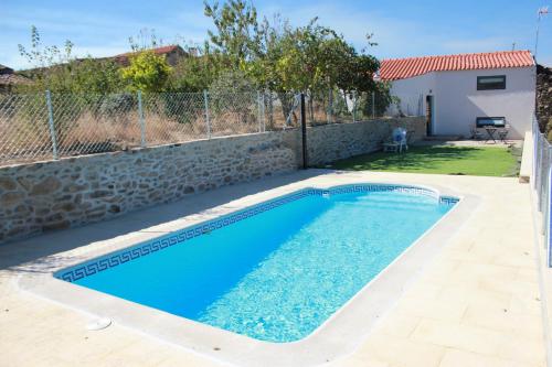 CaçarelhosCurral D Avó Turismo Rural & SPA的一座带石墙的庭院内的游泳池