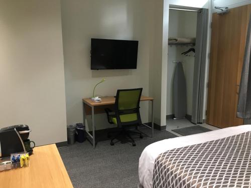埃德蒙顿University of Alberta - PLH Accommodation的客房设有床、书桌和电视。