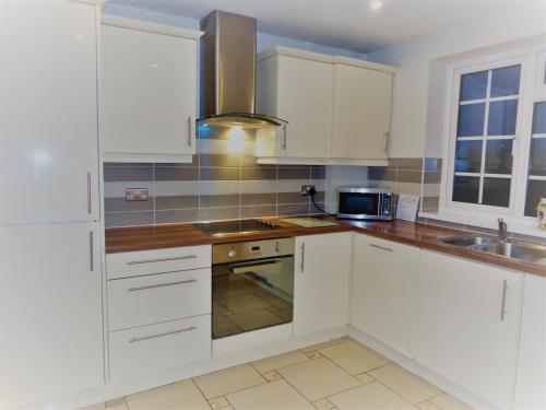 诺丁汉Faraday Place的白色的厨房配有白色橱柜和水槽
