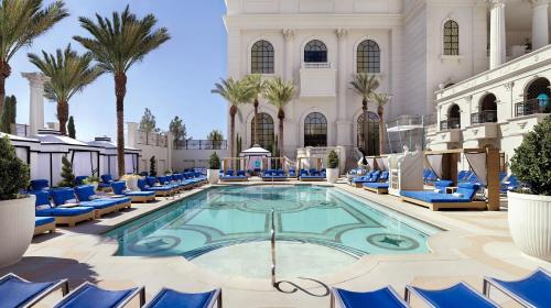 拉斯维加斯凯撒宫赌场度假酒店的大堂的游泳池,设有蓝色椅子和棕榈树