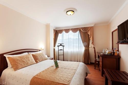 帕斯托费尔南多广场酒店的一间卧室配有一张床、一张书桌和一个窗户。