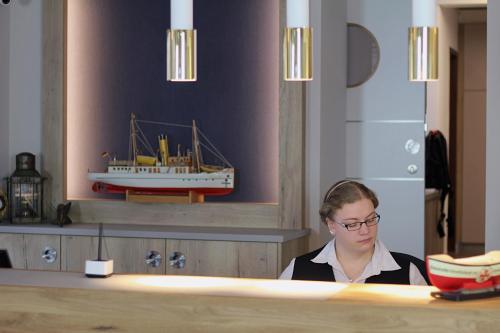 库克斯港伍赫伯格酒店的坐在柜台上的女人,墙上有一条船