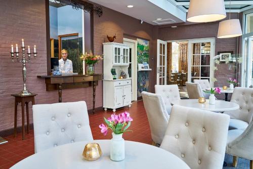 梅赫伦布露酒店的一间设有白色桌椅的餐厅,一间设有镜子的女人