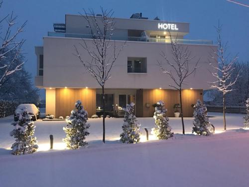 萨格勒布Hotel Magdalena的一座建筑前有雪覆盖的树木的酒店