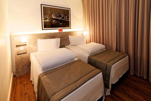 圣保罗Ramada Encore Sao Paulo Tiradentes Centro的酒店客房,设有两张床和窗帘
