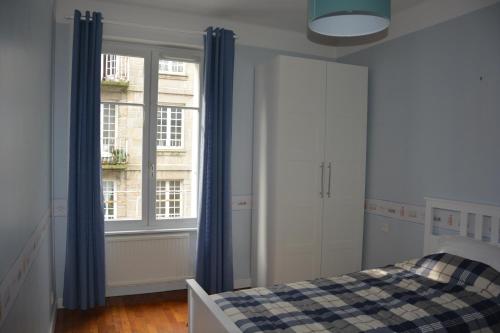 圣马洛Jacques MELCHIOR meublé de tourisme 3 étoiles Intra Muros的一间卧室配有床和蓝色窗帘的窗户