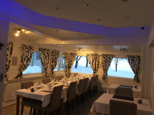 拉科维察祖潘之家酒店的餐厅设有白色的桌椅和窗户。
