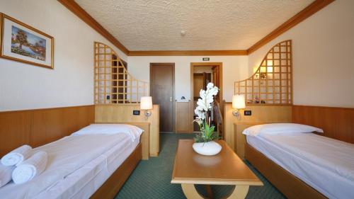 利维尼奥尹特尔蒙缇酒店的一间设有两张床的房间和一张鲜花桌子