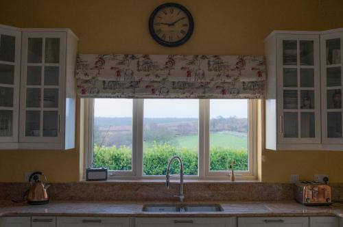 GreencastleThe Doc's self catering的厨房窗户上方设有水槽上的时钟