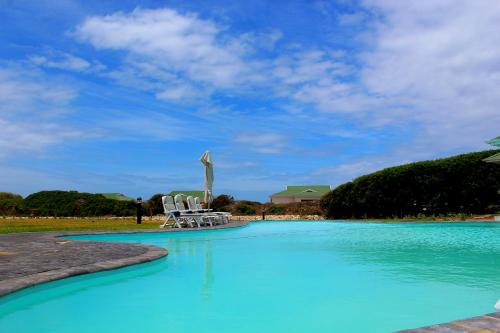 GouritzmondGourikwa Nature Reserve的一个带椅子的游泳池和一个十字形雕像