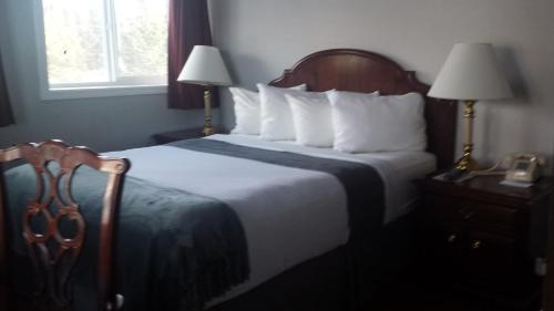 荷马贝鲁加湖旅舍的一张位于酒店客房内的床铺,配有两盏灯和一部电话