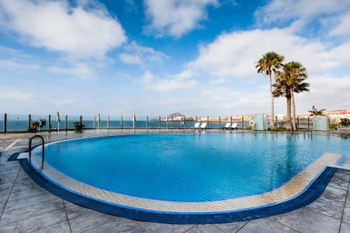 厄尔梅达诺Kn Hotel Arenas del Mar Adults Only的一座棕榈树和海洋的大型游泳池