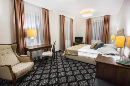 ToszekHG Hotel的酒店客房配有一张床、一张桌子和一把椅子。