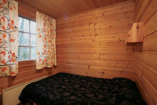 耶姆赛Koivula Cottages的木制客房内的一间卧室,配有一张床