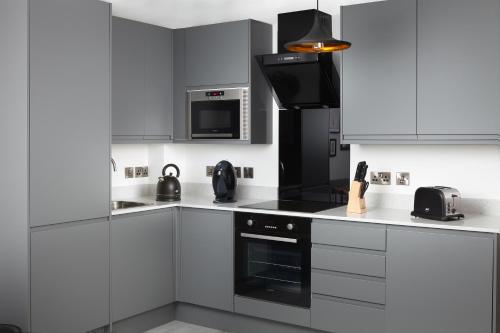 赫尔We Love HU的厨房配有白色橱柜和黑炉灶烤箱。