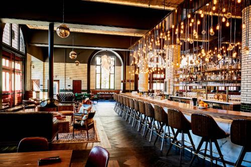 底特律Detroit Foundation Hotel的餐厅设有配备椅子和吊灯的酒吧