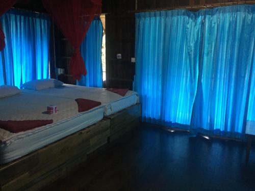 考索竹楼酒店的一间卧室配有蓝色窗帘和一张床