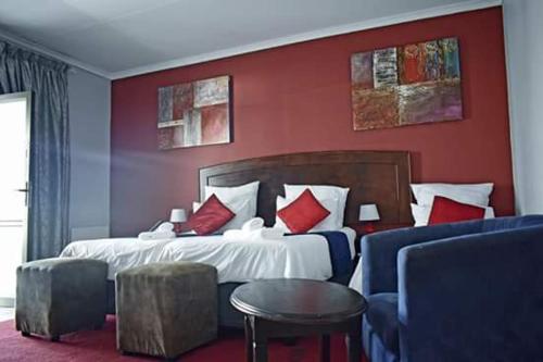 布隆方丹Ehrlichpark Lodge self catering and spa的一间卧室设有一张带红色墙壁的大床